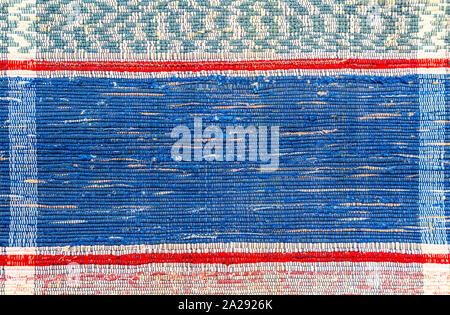 Old handmade doormat from strips of cloth as background. Texture of a homespun rug from different fabrics Stock Photo