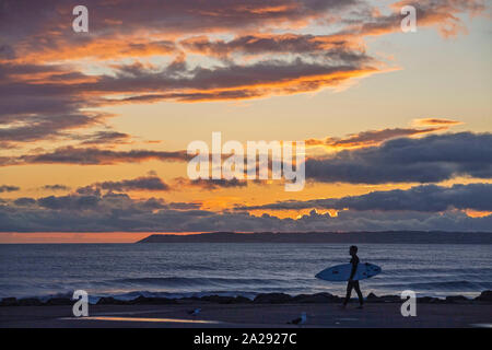 Port Talbot, UK. 01st Oct, 2019. A surfer at Aberavon Beach in Port Tallbot watches as the sun goes down across the water at Swansea this evening duting a break in the wet and windy weather. Credit: Phil Rees/Alamy Live News Stock Photo