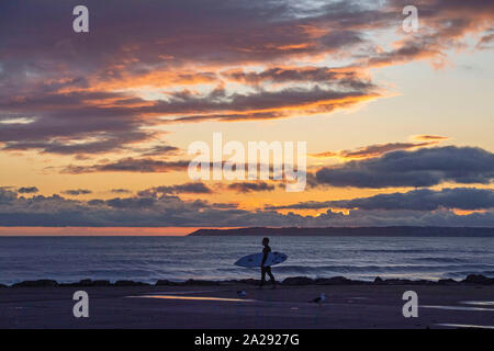 Port Talbot, UK. 01st Oct, 2019. A surfer at Aberavon Beach in Port Tallbot watches as the sun goes down across the water at Swansea this evening duting a break in the wet and windy weather. Credit: Phil Rees/Alamy Live News Stock Photo