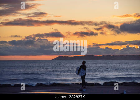 Port Talbot, UK. 01st Oct, 2019. A surfer at Aberavon Beach in Port Tallbot watches as the sun goes down across the water at Swansea this evening duting a break in the wet and windy weather. Credit: Phil Rees/Alamy Live News Stock Photo