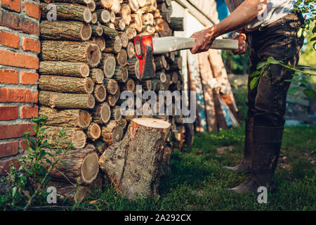 Working with ax. Senior man chopping firewood with an axe in countryside yard. Stock Photo