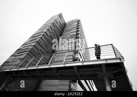 Man stood on a bridge outside a modern apartment block, Saint George’s Island, Castlefield, Manchester, UK Stock Photo