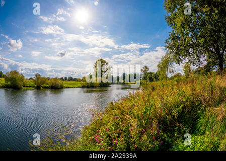 Landschaft im Sommer mit Fluss, Bäumen und Wiesen bei strahlendem Sonnenschein Stock Photo
