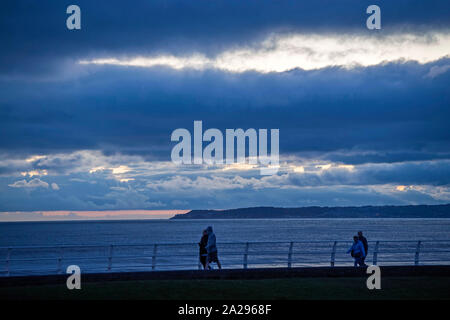 Port Talbot, UK. 01st Oct, 2019. Port Talbot - UK - 1st October 2019 : People out walking as the light starts to fade on the seafront at Aberavon Beach, Port Talbot this evening. Credit: Phil Rees/Alamy Live News Stock Photo