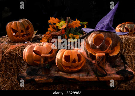 Jack lamp for pumpkin Halloween celebration. Festive composition of pumpkins with carved scary faces with luminous eyes and candles. All Saints' Day. Stock Photo