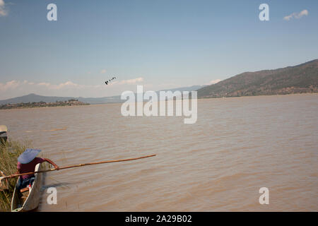 The man paddles while wearing a blue hat to protect himself from the sun Stock Photo