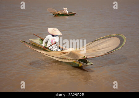Pair of fishermen paddling to move their canoes loaded with fishing nets sailing through lake in Michoacán Mexico spontaneous photography Stock Photo