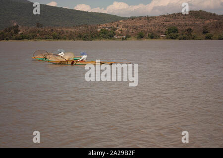 Pair of fishermen paddling to move their canoes loaded with fishing nets sailing through lake in Michoacán Mexico spontaneous photography Stock Photo