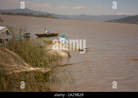 Pair of fishermen paddling to move their canoes sailing through lake in Michoacán Mexico spontaneous photography Stock Photo