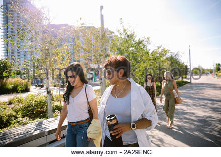 Mature women friends walking in sunny city park
