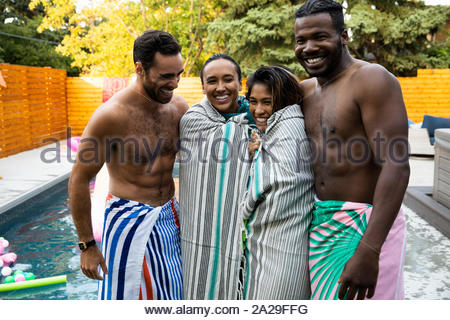 Portrait happy, carefree young couples wrapped in towels at summer poolside