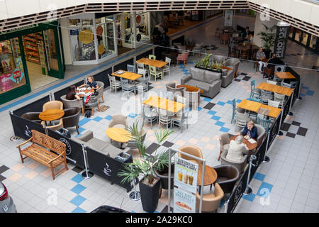 UK looking down at people sat at tables eating and drinking at a food court in a shopping centre or shopping mall Stock Photo