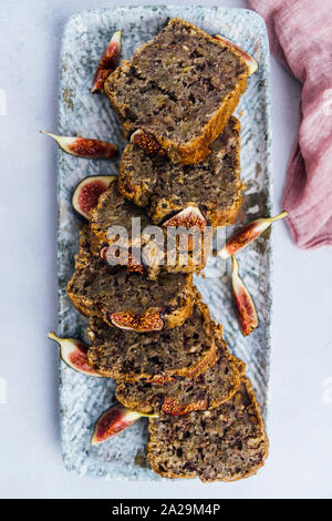 Fig bread recipe with banana, fresh figs and walnuts sliced on a rectangular plate. Stock Photo
