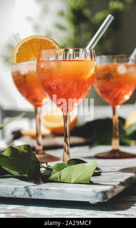 Aperol Spritz aperitif alcohol cocktail in glasses with fresh oranges and ice on grey marble board, selective focus, vertical composition. Summer refr Stock Photo