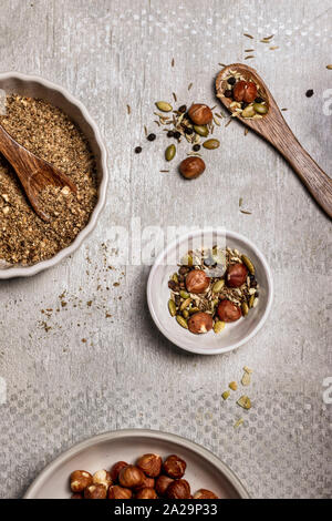 Assortment of spices, seeds and nuts in bowls on gray background Stock Photo
