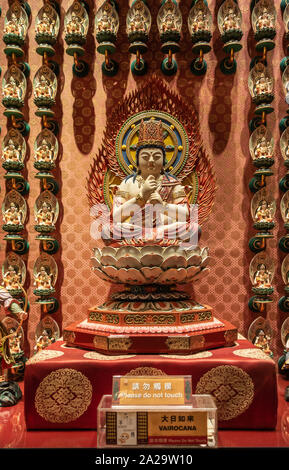 Singapore - March 22, 2019: Buddha Tooth Relic Temple in Chinatown. Vairocana, celestial Buddha, statue with backdrop of many small statues. Stock Photo