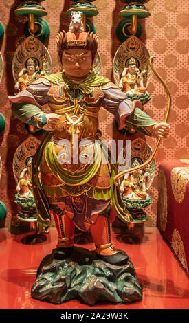 Singapore - March 22, 2019: Buddha Tooth Relic Temple in Chinatown. Fierce looking and colorfully multicolor painted statue of guardian, knight, and p Stock Photo