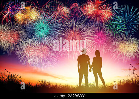 young couple watching fireworks on hill Stock Photo