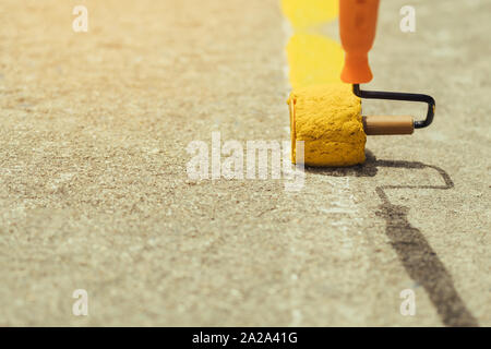 Male students use small paint rollers to paint yellow lines on the cement floor for Sepak Takraw training. Stock Photo