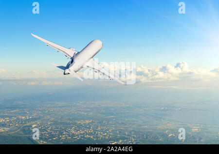 Airplane gains altitude flying into the distance flies over the city, rear view Stock Photo