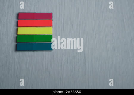A set of colored bookmarks lies on a table horizontally on a light painted surface. Stripe stickers. Flat lay. Red, yellow, green, blue. Copy space. Stock Photo