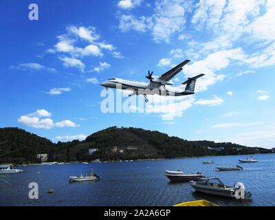 A Greek Olympic aircraft approaches Skiathos airport flying low over the sea on its approach. Stock Photo