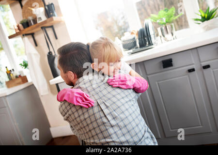 Lovely girl hugging father while cleaning kitchen together Stock Photo