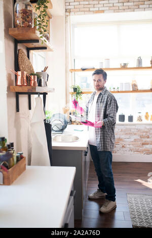 Mature man wearing checked shirt washing dishes Stock Photo