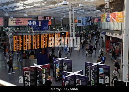 A busy morning at Manchester Piccadilly Station showing the large departures display board on the station concourse Stock Photo