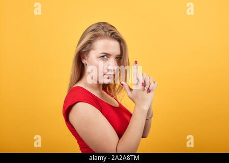 young blonde girl in red t-shirt over isolated orange background shows emotions Stock Photo