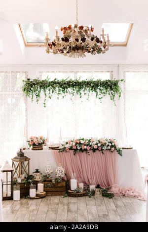 Lights, wooden parts and white candles stand on a parquet near the groom and bride desk Stock Photo