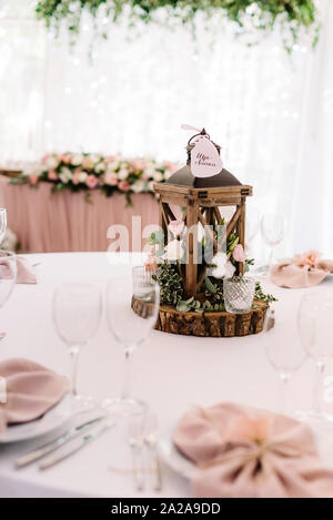 The beautiful, original decor of wood, flowers and candles stands in the middle of the dining table Stock Photo