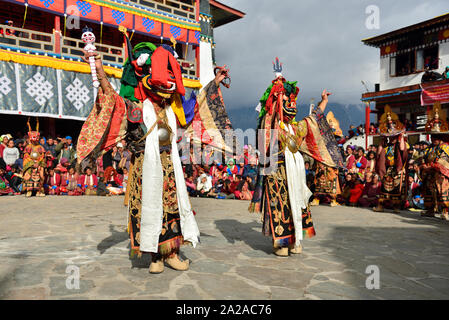 Tawang, Arunachal Pradesh, India, Buddhist monk dancing in disguise for the Torgya  festival, in the background there are  monastery and many gathered Stock Photo