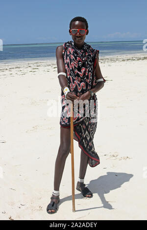 Maasai man with cane standing on the beach, Zanzibar, Unguja Island, Tanzania. Stock Photo