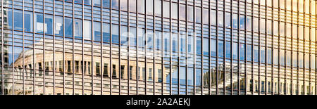 Panoramic of a modern glass building at sunset with clouds reflecting in the glass windows Stock Photo