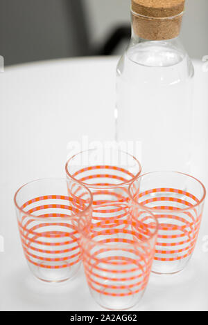 Four glasses and a jar of water on a modern work desk ready for a meeting Stock Photo