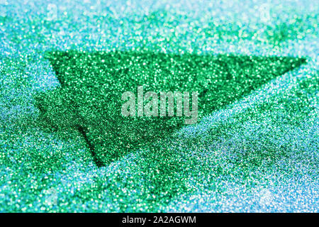 Green arrow shape made of glitter on sparkly blue paper, selective focus Stock Photo