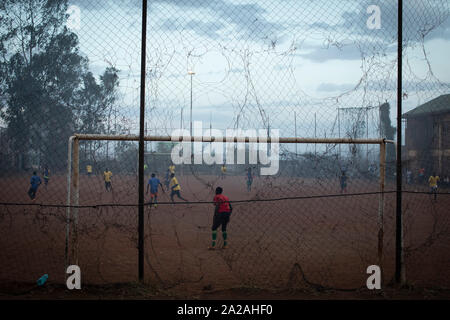 Young men play a football match in a pitch filled with smoke blowing from the Dandora dumpsite, in the slum of Korogocho in the capital Nairobi, Kenya. Stock Photo