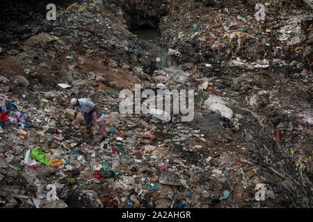 A man picks plastic for recycling as polluted water drains into the Buriganga river in the capital Dhaka, Bangladesh, April 27, 2019. Stock Photo