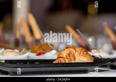 Tasty croissant sandwich with cheese and ham in black plate, Party Appetizer Stock Photo