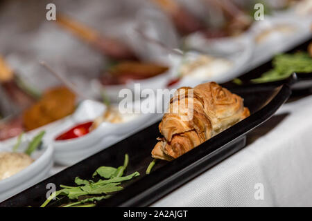 Tasty croissant sandwich with cheese and ham in black plate, Party Appetizer Stock Photo