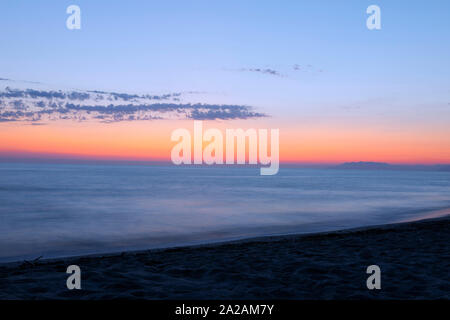 Long exposure sea landscape with dusky pink sky. Seascape  with sunset sky and motion blur water. Marina di Torre del Lago Puccini, Italy. Stock Photo
