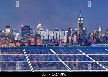 Blue solar cell panels, New York skyline illuminated at night in the background Stock Photo