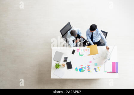 two businessmen in the office are sitting at the chair. One man holding a tablet and pen and another pointed to the screen. they are analyzing, brains Stock Photo