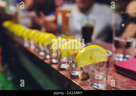 Bartender pouring strong alcoholic drink into small glasses on bar, shots. Stock Photo