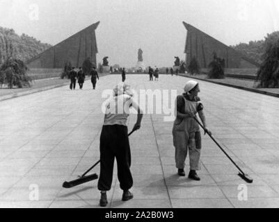 Two workers sweep the square in front of the Soviet Memorial in Berlin-Treptow, in the background is the memorial. Stock Photo