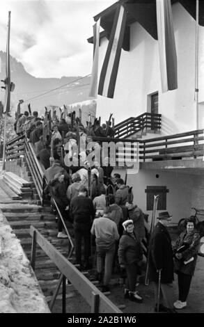 View of waiting skiers who want to take the cable car up to the Hahnenkamm. The picture was taken on the occasion of the Hahnenkamm race taking place at the same time, and was held on one of the pistes. The Hahnenkamm race has been held since 1931 on the Hahnenkamm in Kitzbuehel. Stock Photo