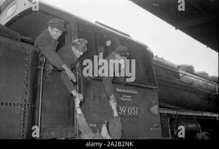 The interzonal train on the route Leipzig-Gutenfuerst-Hof-Munich after its arrival at the border station. This train was known for its 'all-German' dining car, which was popular due to the 1: 1 exchange rate, especially among East German travelers. Photo of train drivers of the Deutsche Reichsbahn welcoming their West German colleague. Stock Photo