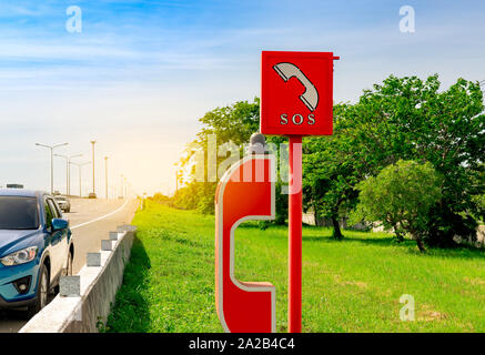 Blue SUV car parked at roadside near emergency SOS telephone. Highway SOS call box. Motorway emergency roadside call system. Emergency phone for help Stock Photo