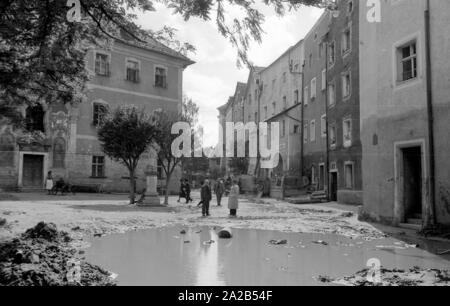 The flood in Passau and other parts of Lower Bavaria (July, 1954) were also referred to as the flood of the century. The Danube, the Inn and the Ilz had overflowed their banks, and flooded towns and villages. Photo of a last pond of water and alluvion. After the flood residents carry their destroyed furniture outside . Stock Photo
